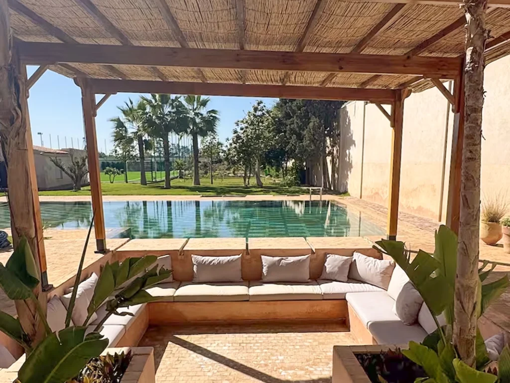Espace détente ombragé avec piscine et palmiers dans une retraite bien-être au Maroc