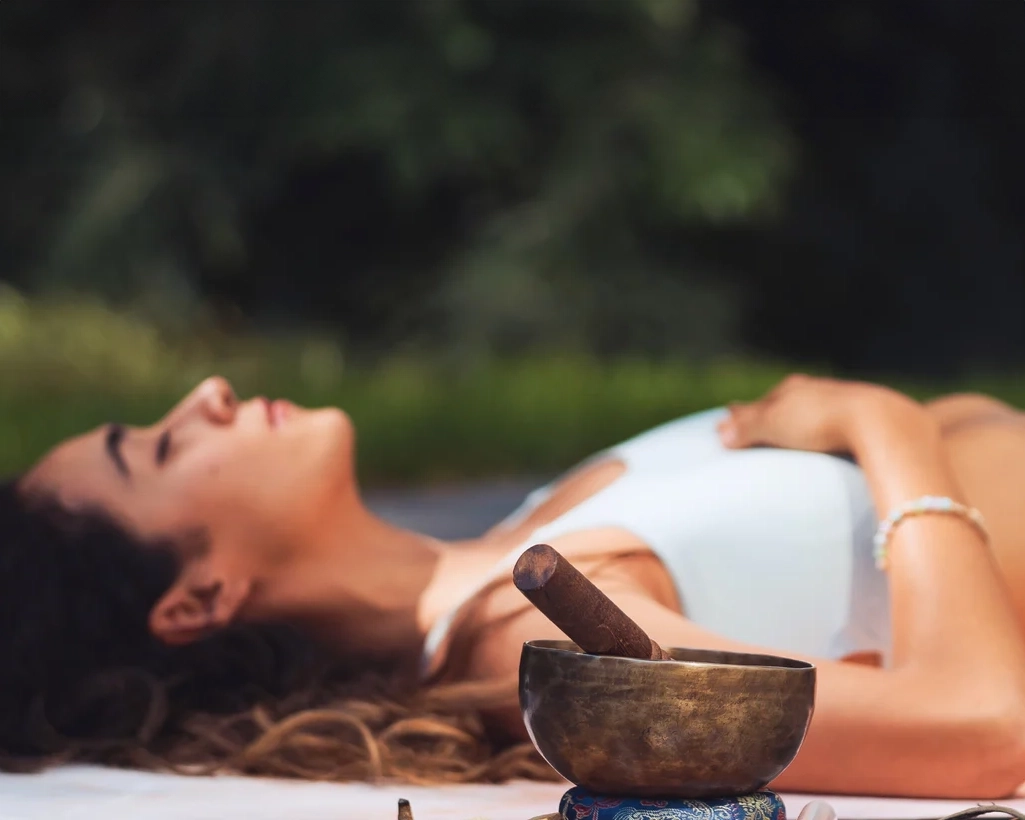Femme allongée en méditation avec un bol tibétain lors d’une session de sound healing en pleine nature