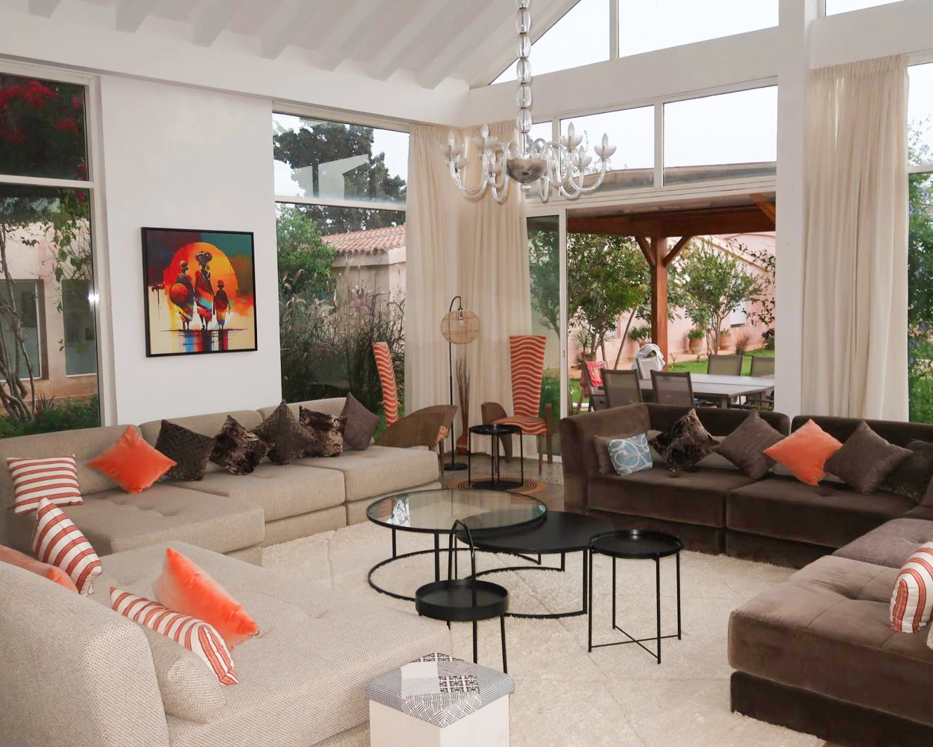 Salon lumineux et chaleureux de la maison Ômri, avec canapés confortables, baies vitrées et vue sur le jardin
