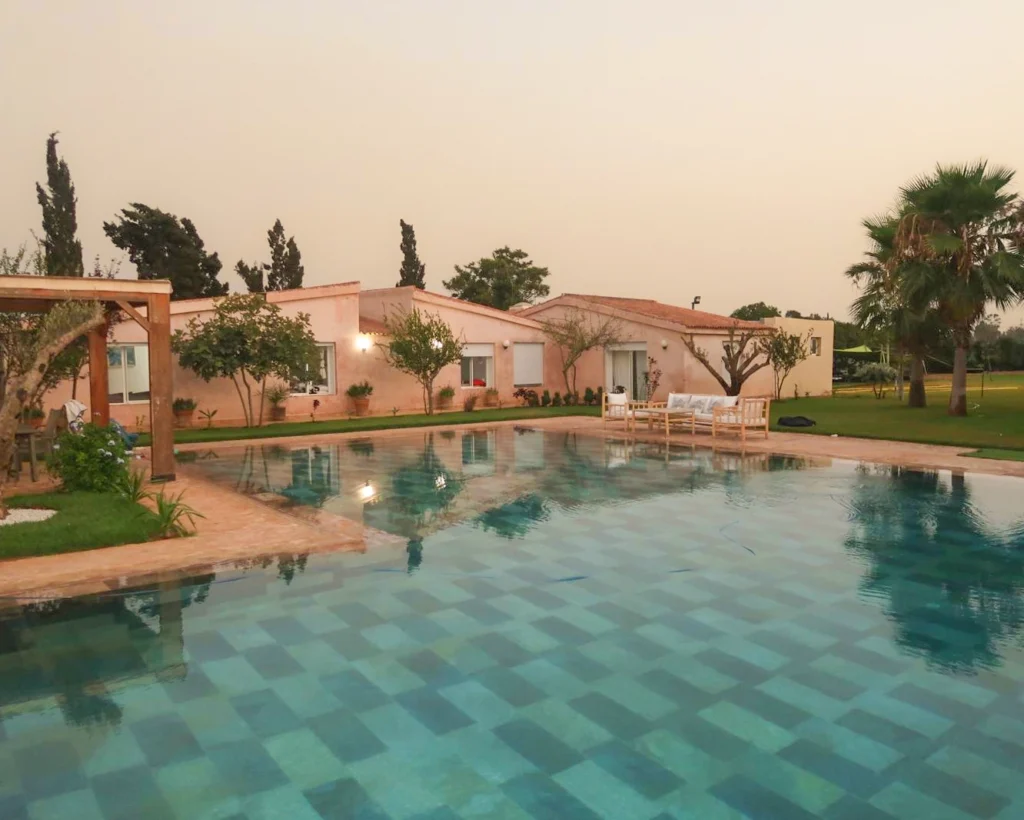 Vue extérieure de la maison Ômri au coucher du soleil, avec piscine et espaces verts dans un cadre paisible à Tamaris