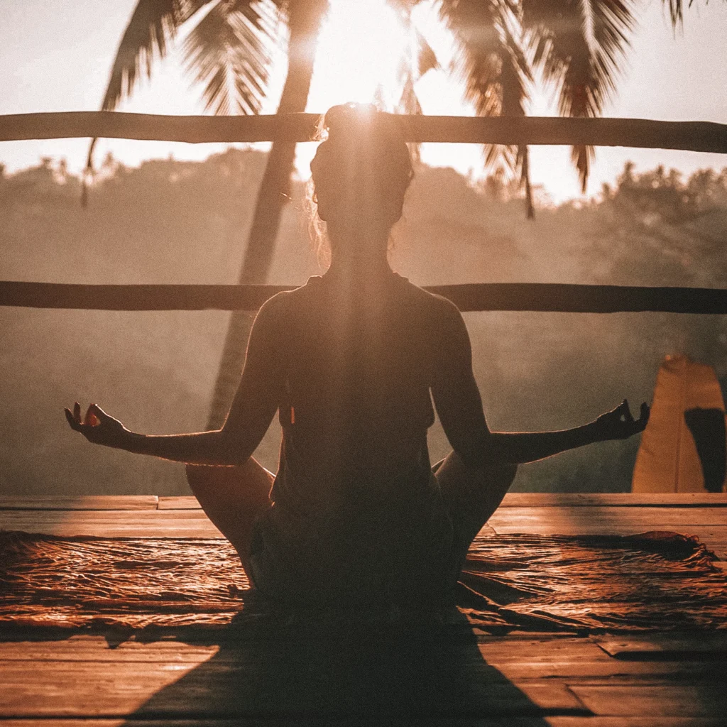 Femme en méditation au lever du soleil pendant une retraite bien-être en pleine nature tropicale