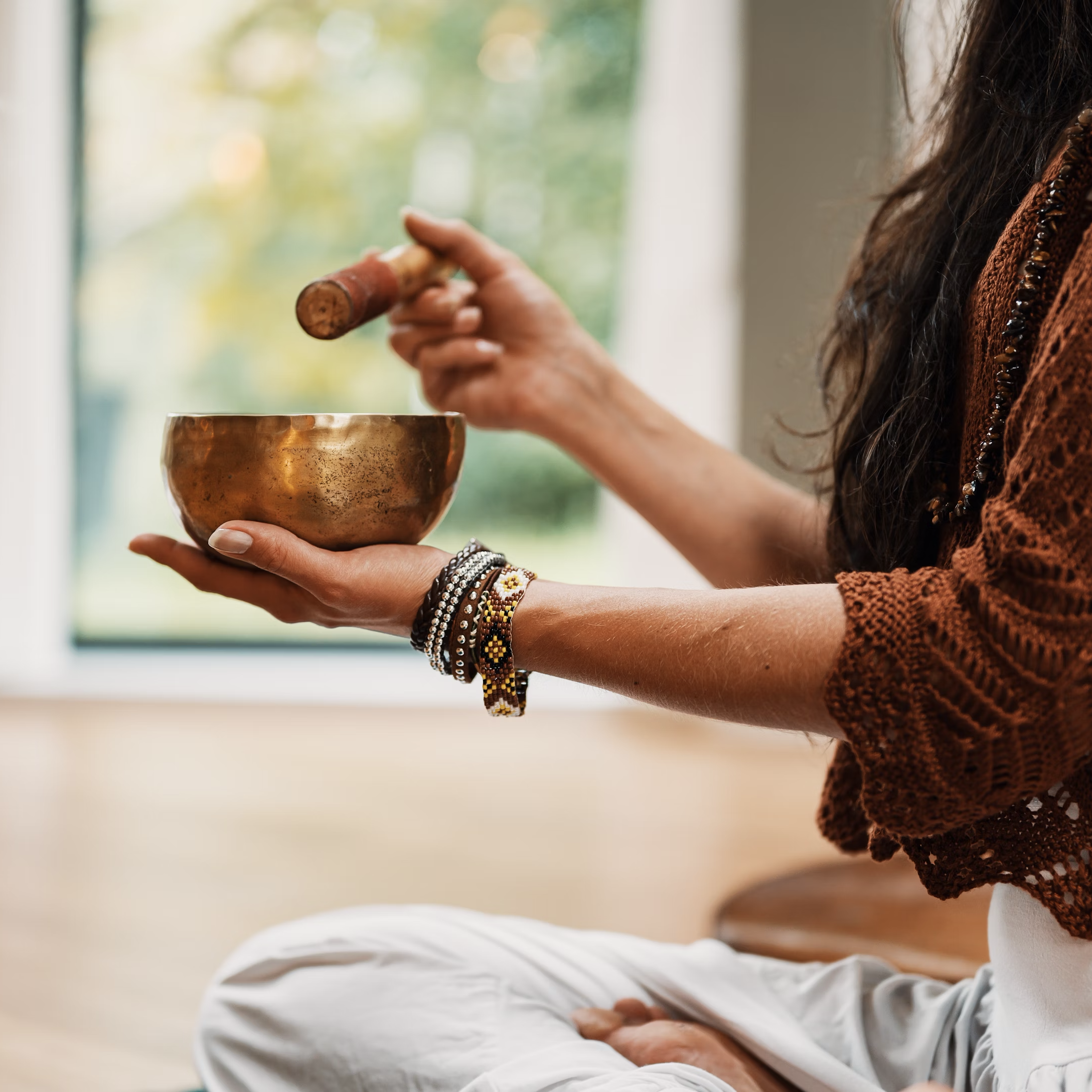 Femme pratiquant le sound healing avec bol tibétain lors d’une retraite bien-être au Maroc
